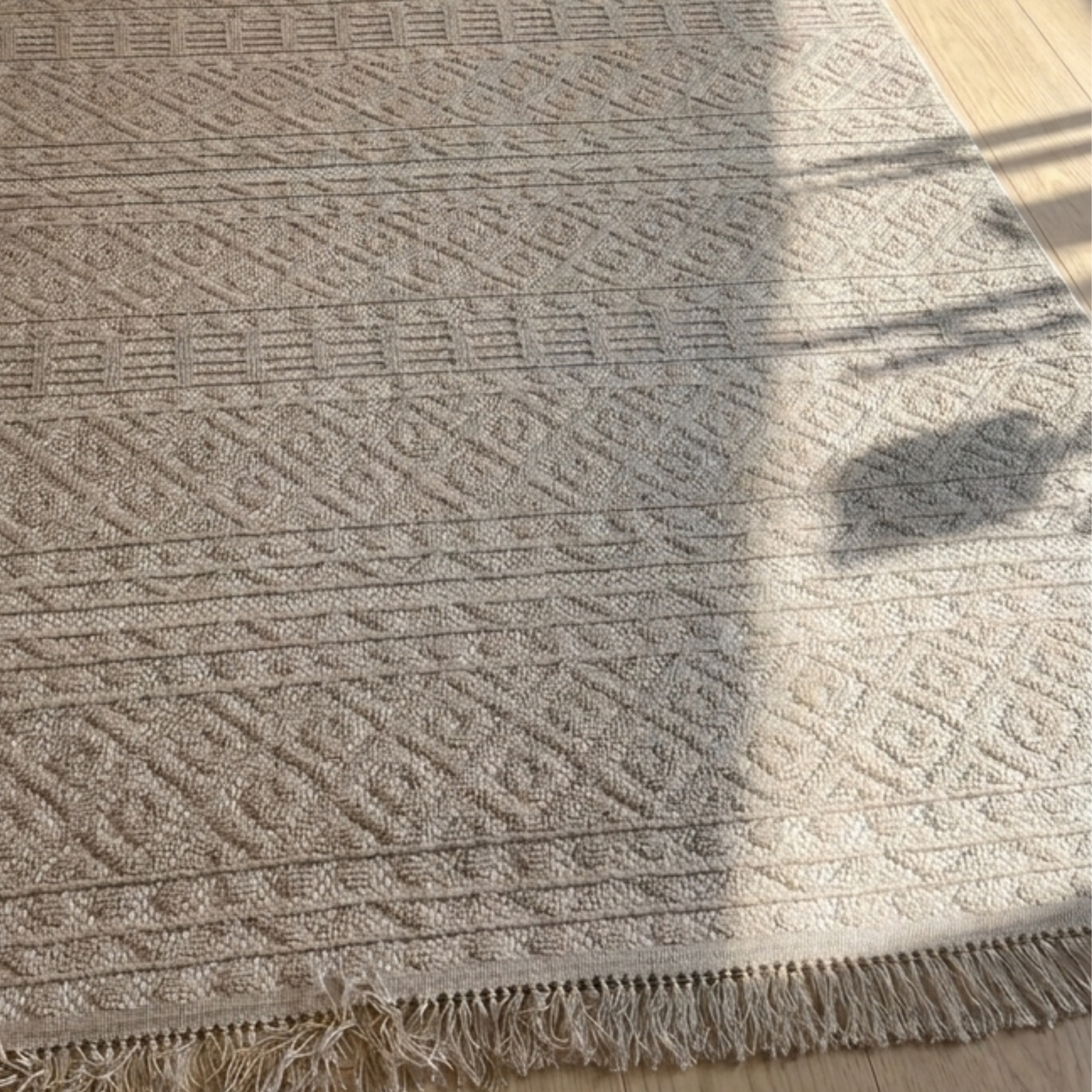 Textured beige rug with geometric pattern on a wooden floor